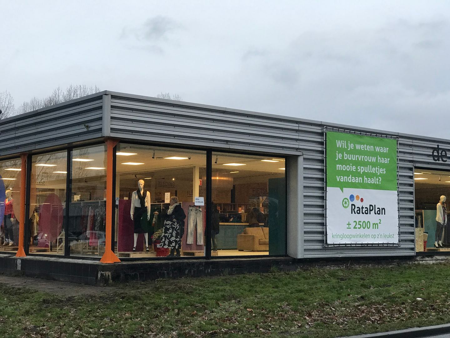 Glazen pui van RataPlan Almere-Haven met etalagepoppen en een RataPlan-spandoek aan de gevel