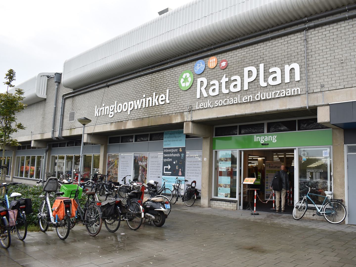 Gevel van Kringloopwinkel RataPlan met naambord, ingang en geparkeerde fietsen