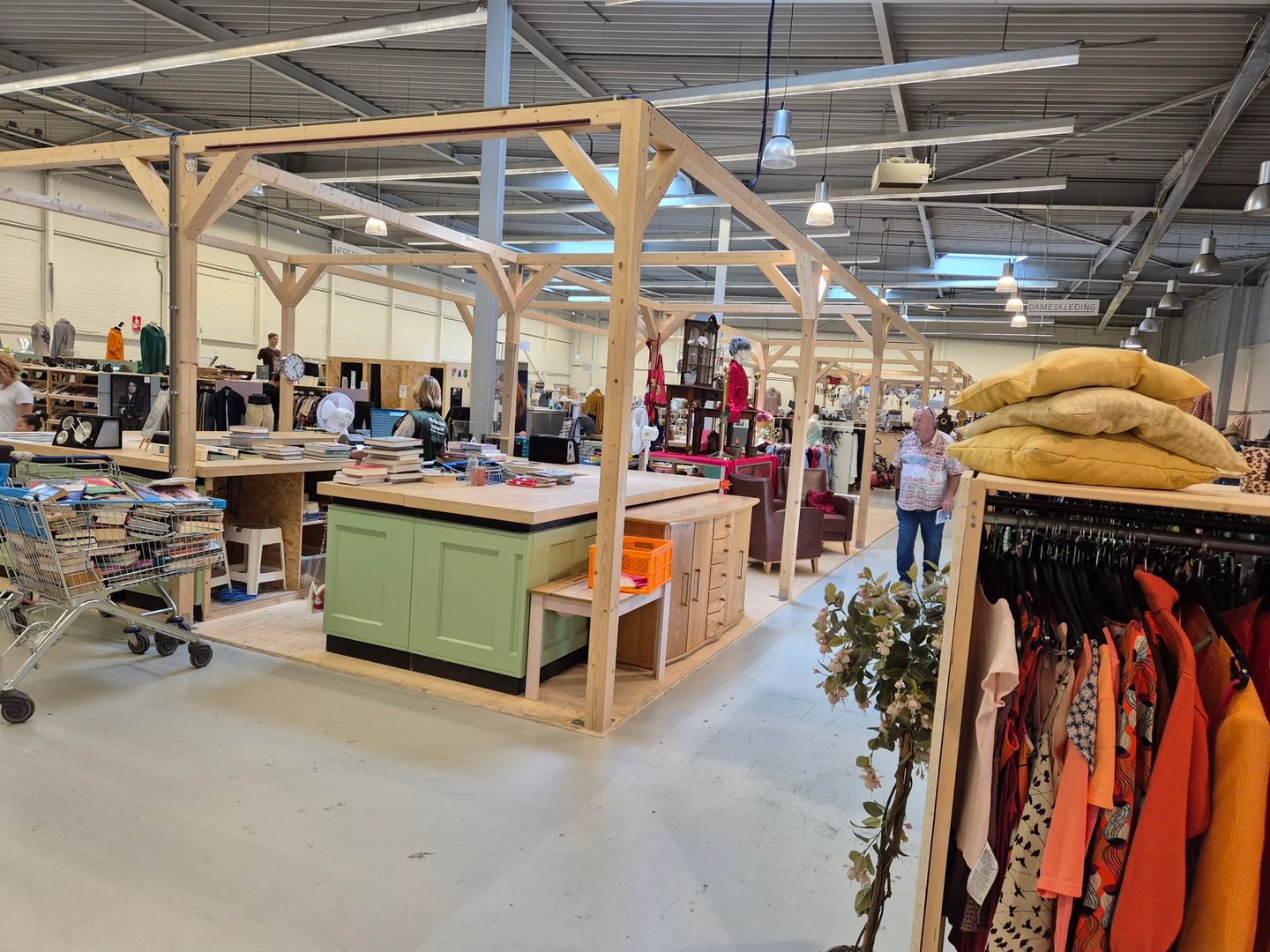 Houten winkelstellingen met kleding, keukenkastjes en boeken in RataPlan Rotterdam