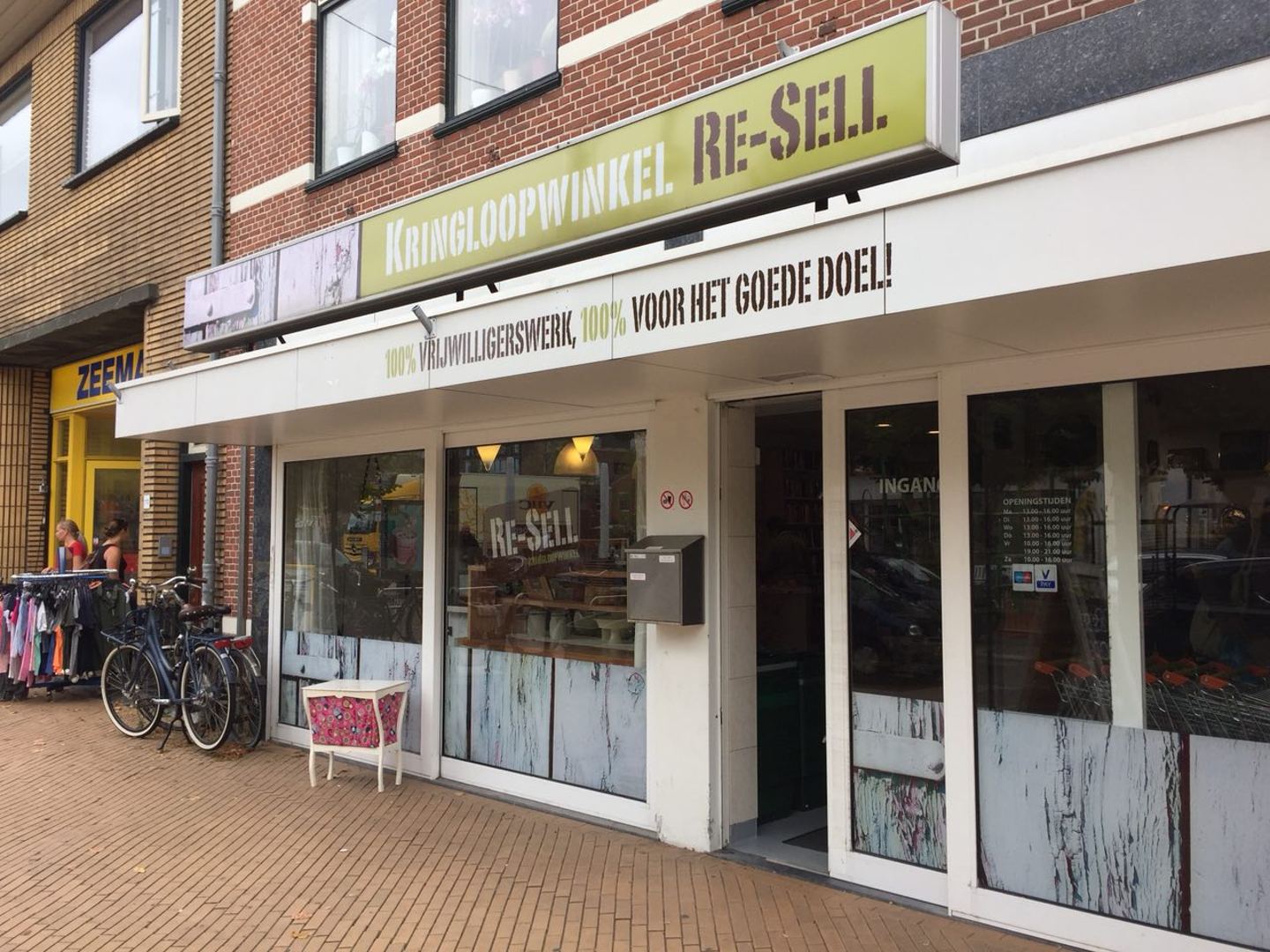 Winkelpui van Re-Sell Kringloopwinkel met het groene naambord, etalages en de ingang