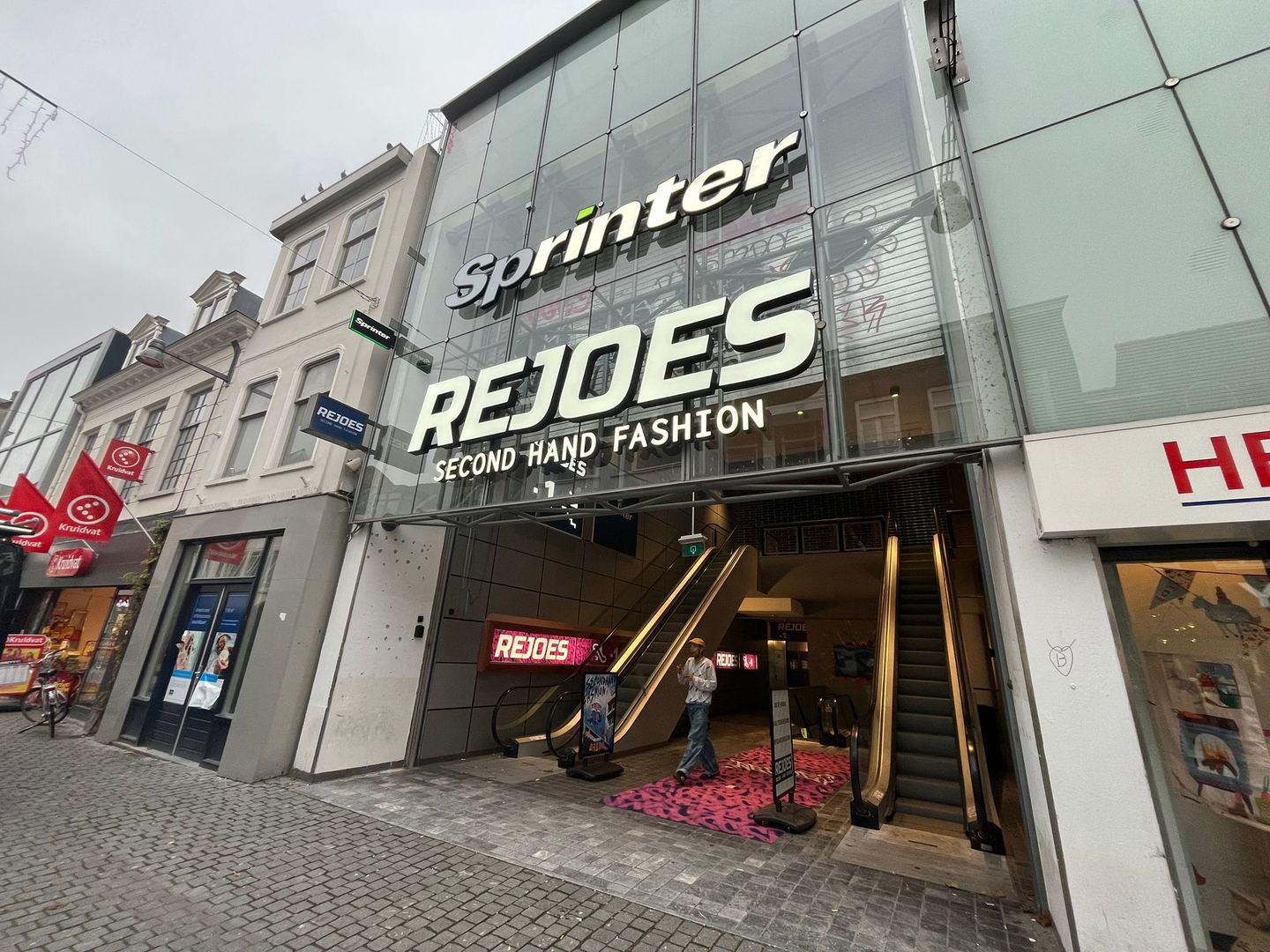 Ingang van Rejoes met groot naambord Second Hand Fashion boven de roltrappen