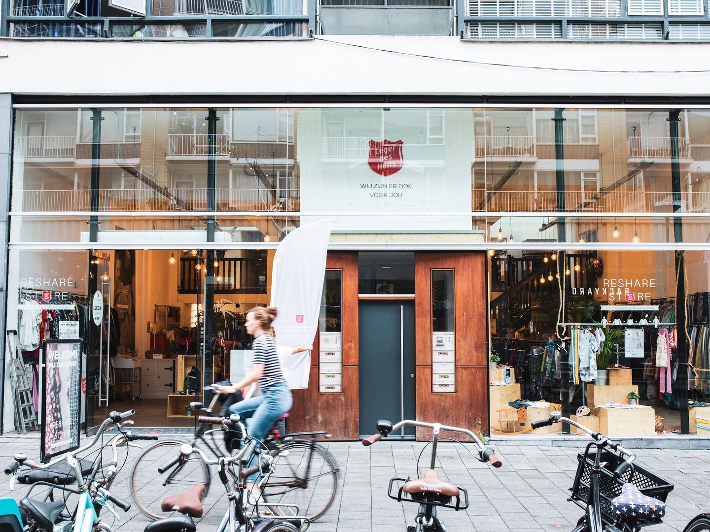 Gevel van ReShare Store Rotterdam met grote etalageramen en rekken met kleding