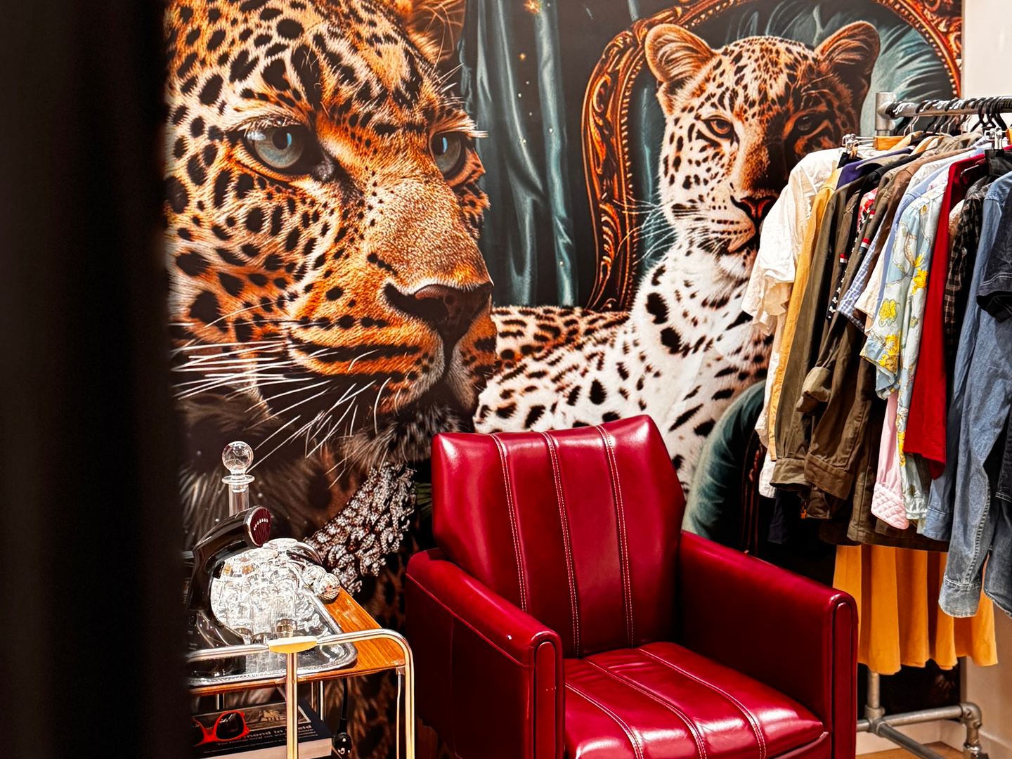 Interieur van Retro Life met rekken vintage kleding, een rode fauteuil en de winkelnaam op de muur
