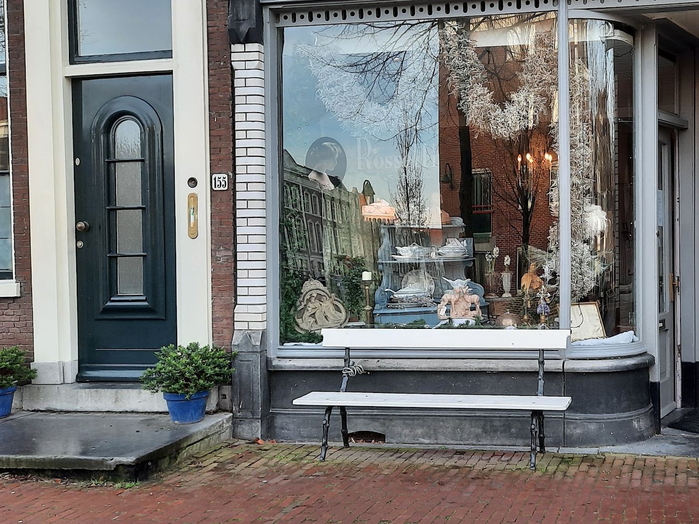 Gevel van Rossetti met grote etalage vol brocante en een wit bankje onder het raam