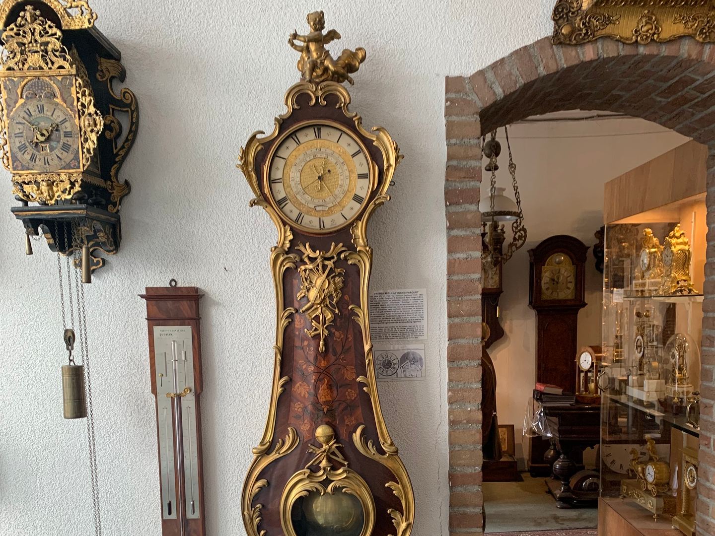Antieke wandklokken, een staande klok en een barometer in de winkel van Schreurs