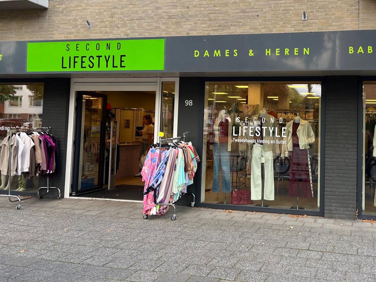 Gevel van Second Lifestyle met groen naambord en etalages vol tweedehands kleding