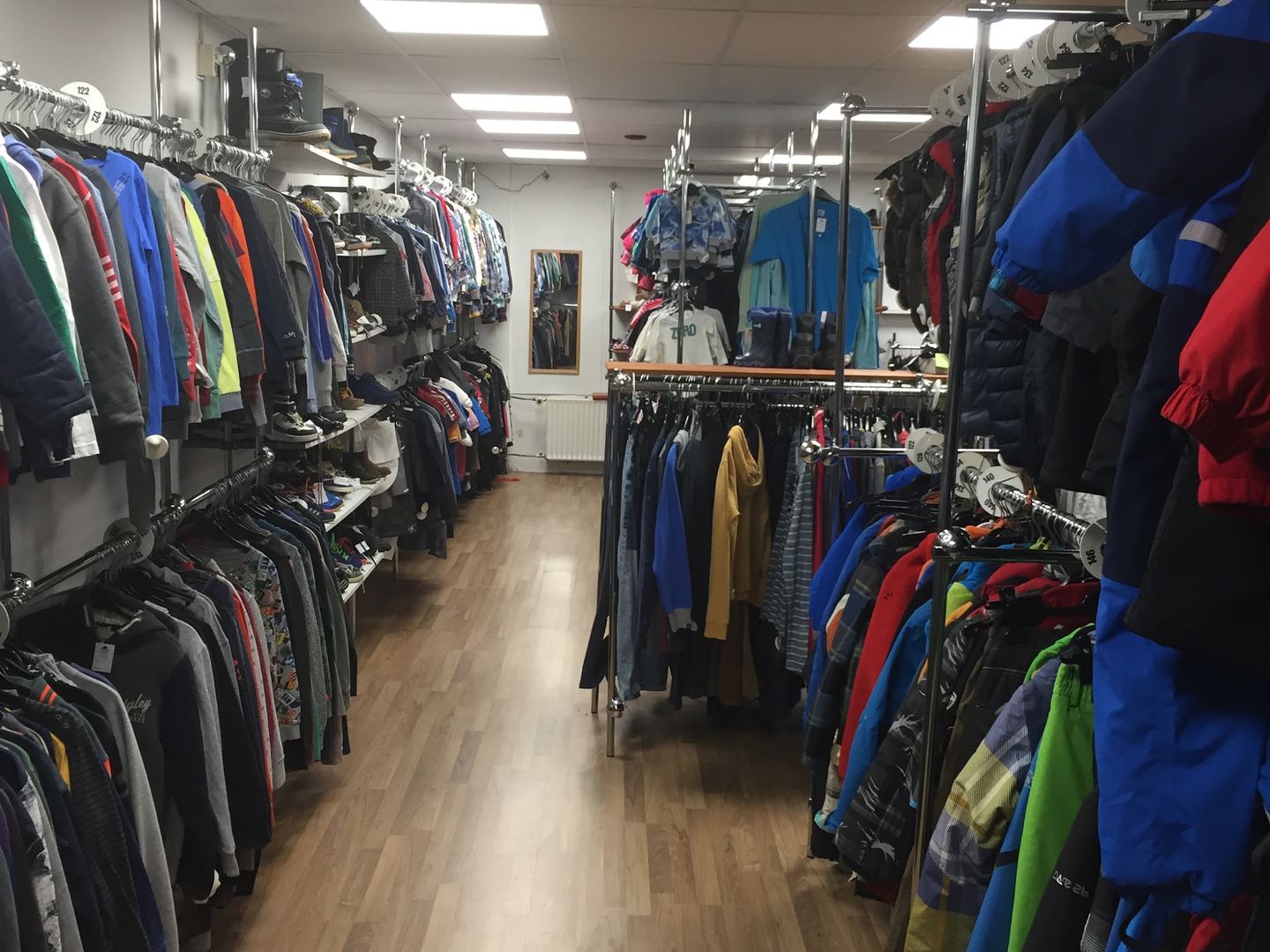 Lange winkelgang met rekken vol tweedehands jassen en kleding in Second Lifestyle Hilversum
