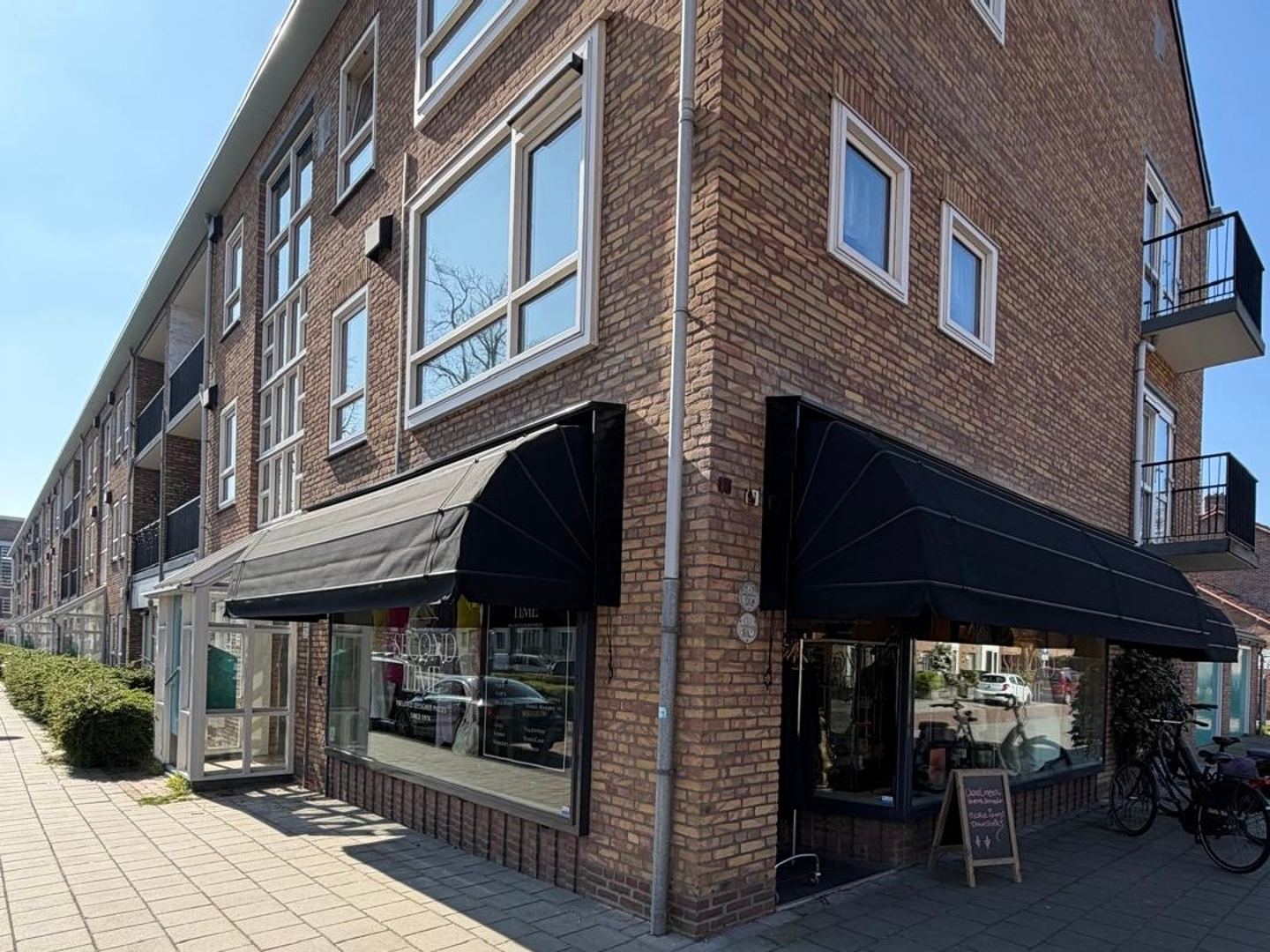 Hoekpand van Second Time met zwarte zonneschermen boven de etalages