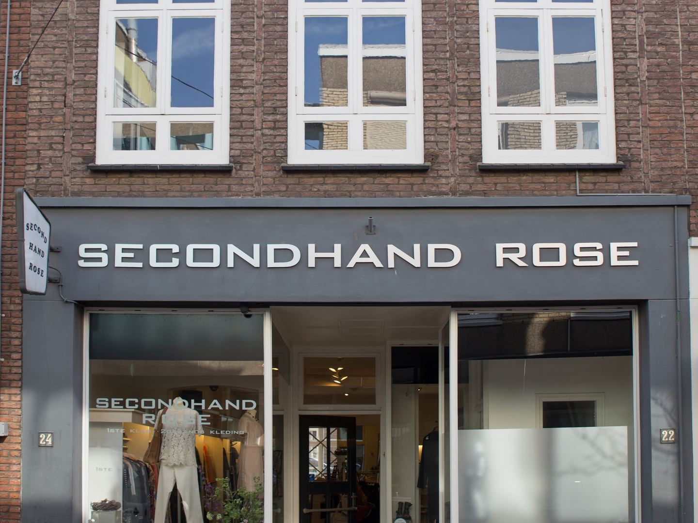 Gevel van Secondhand Rose Nijmegen met naambord boven de etalage