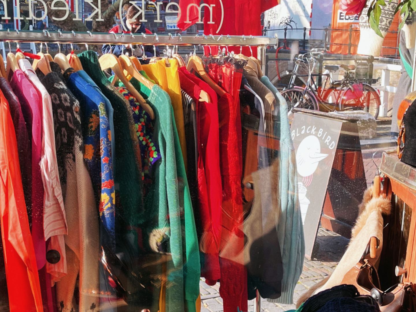 Etalage van Sisters 2ehands met kleurrijke kleding aan rekken, tassen en schoenen
