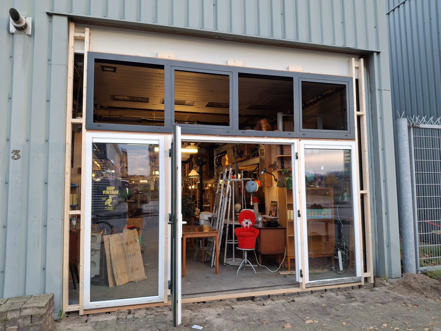 Pui van Snip Vintage in een bedrijfspand met glazen deuren en zicht op vintage meubels