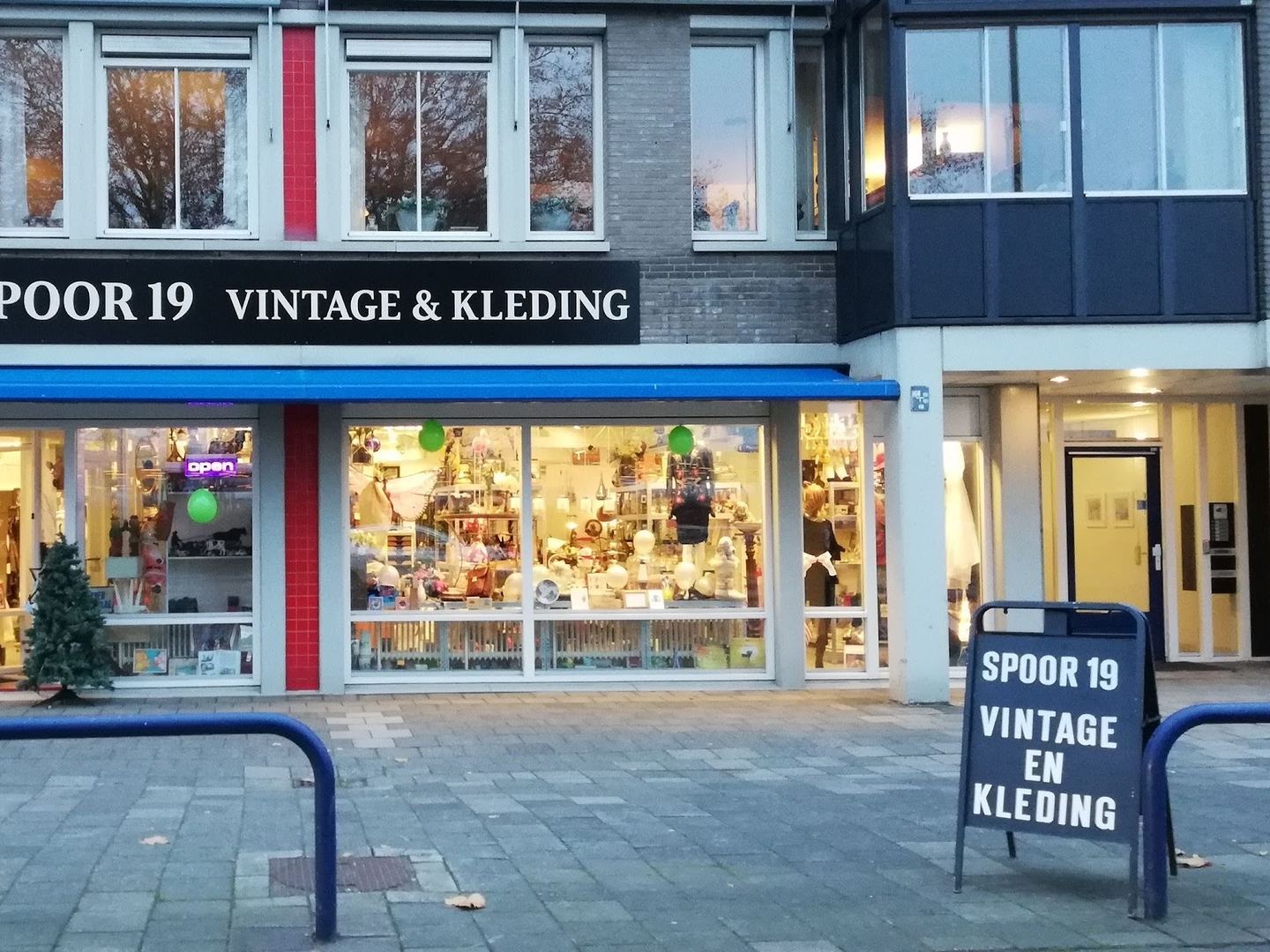 Gevel van Spoor 19 Vintage & Kleding met naambord, etalages en stoepbord