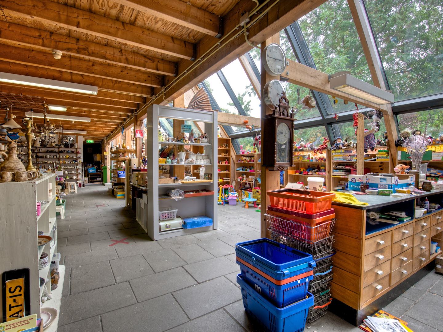 Interieur van Stichting Overal met houten balken, kasten met huisraad en rekken met spullen