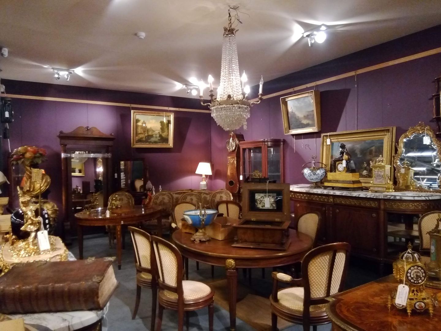Showroom van Strydhagen met antieke meubels, schilderijen, een kroonluchter en pendules