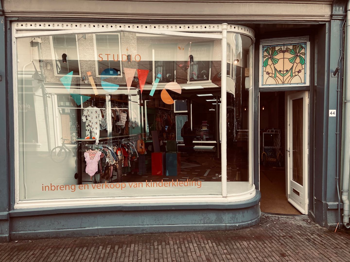 Winkelpui van Studio KieWie met gebogen etalageruit, vlaggetjes en rekken met tweedehands kinderkleding