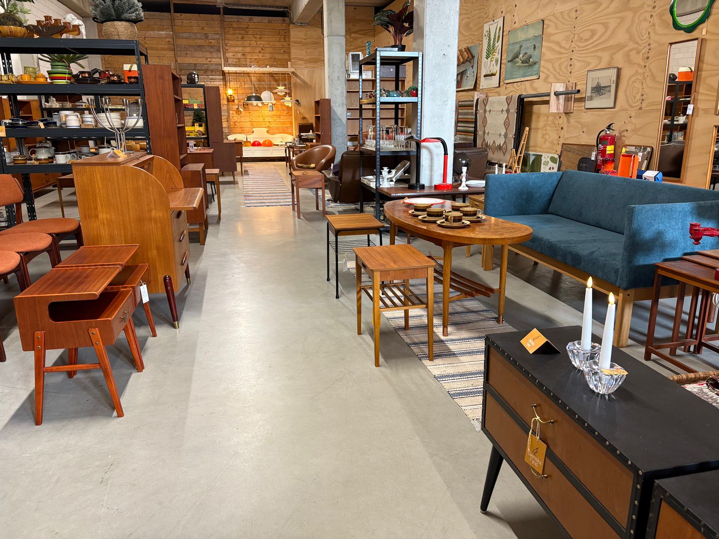 Showroom van Svenska Fynd met teakhouten kasten, salontafels en een blauwe bank