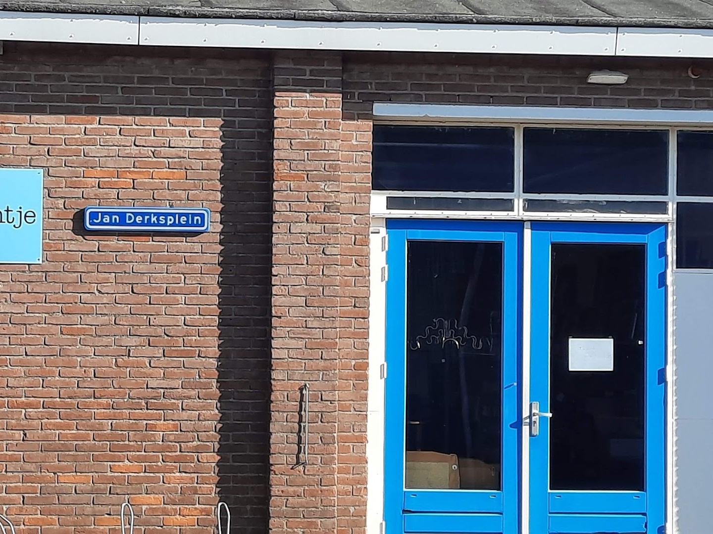 Bakstenen gevel van kringloopwinkel 't VinCentje met naambord en blauwe deuren