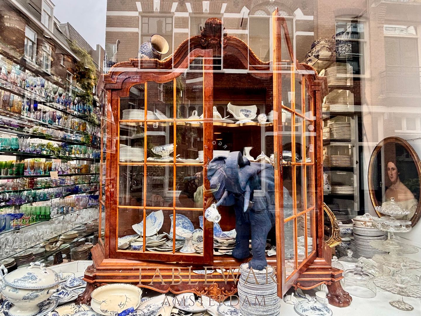 Etalage van Tableware Amsterdam met een antieke vitrinekast vol servies en wanden met glaswerk
