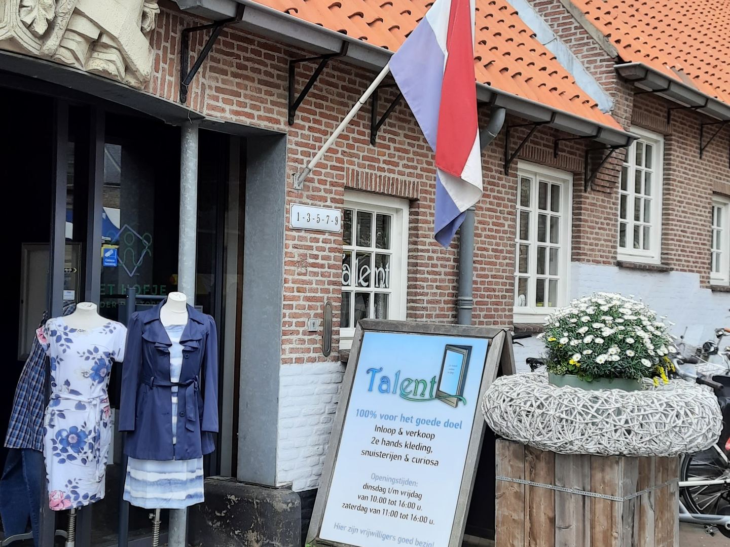 Ingang van Talent in een historisch hofje, met paspoppen, een Nederlandse vlag en een stoepbord
