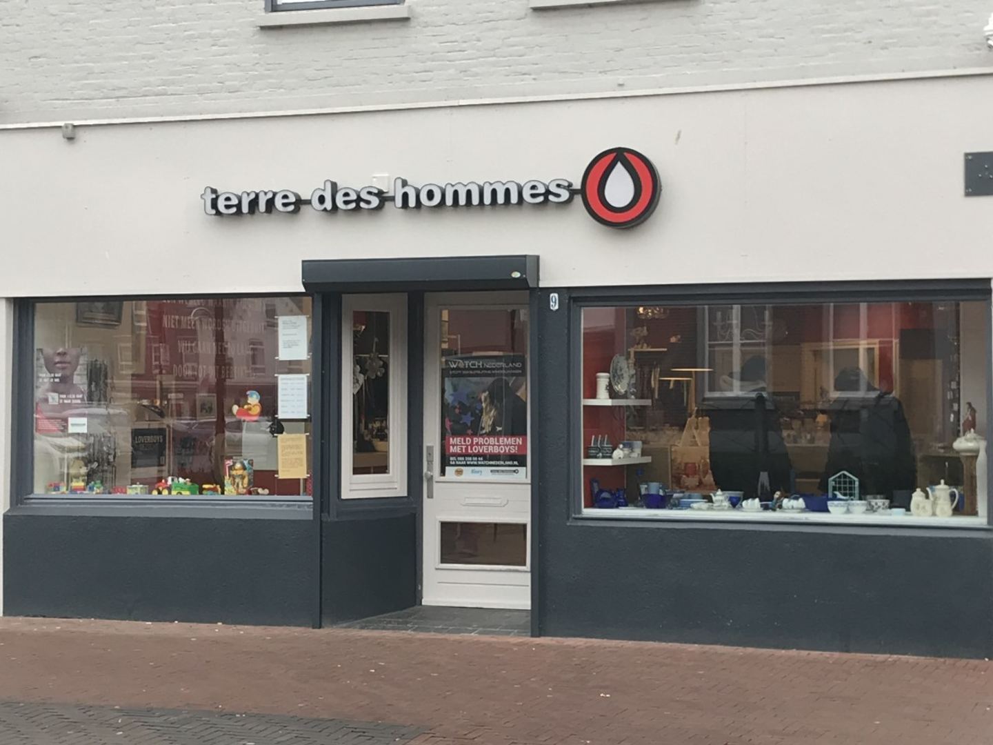 Winkelpui van Terre des Hommes Helmond met naambord en etalages