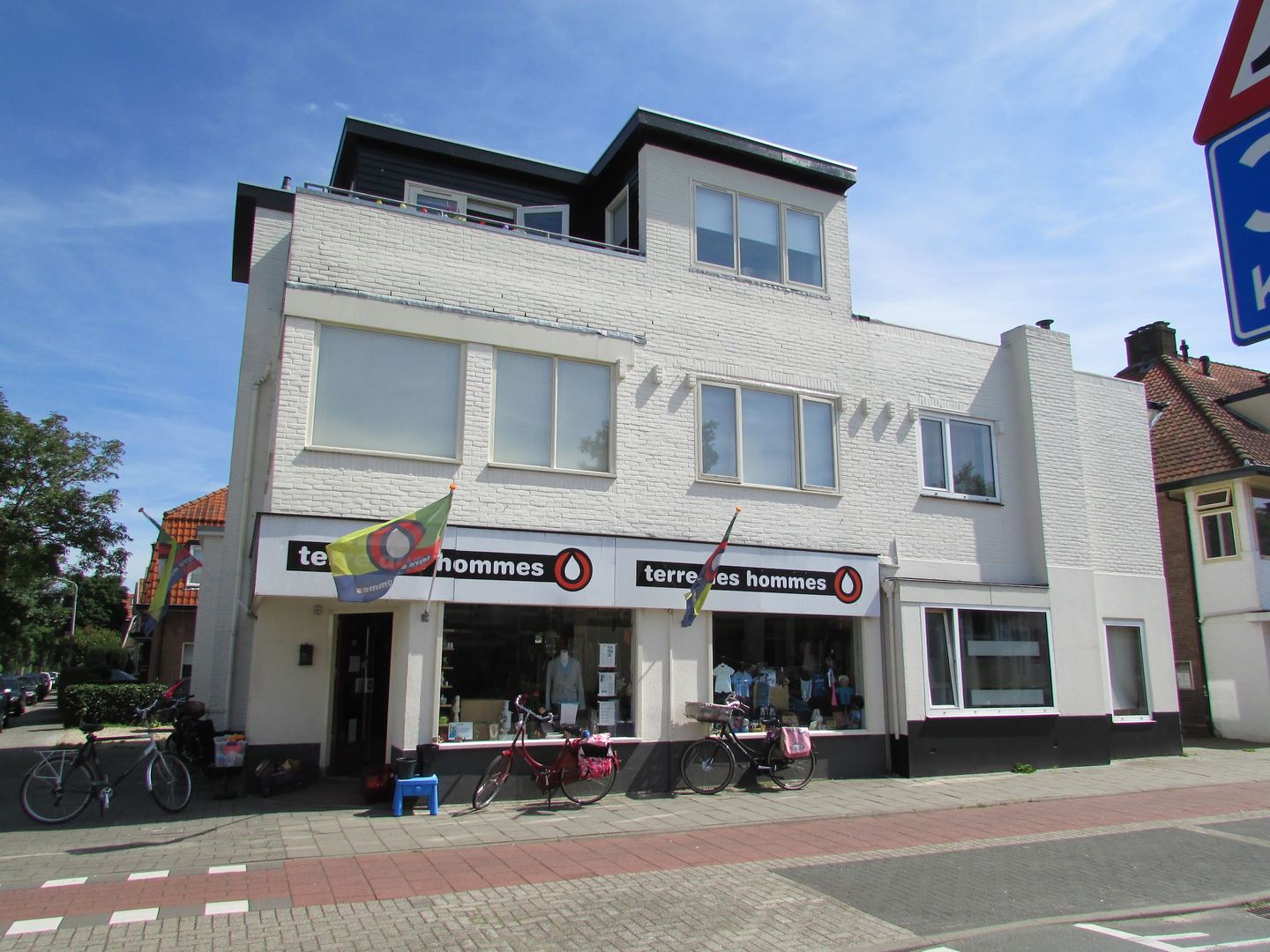 Gevel van de Terre des Hommes-winkel met naamborden en fietsen voor de etalage