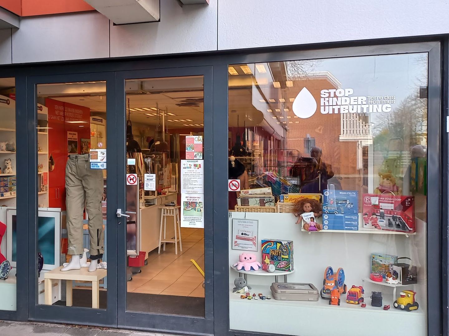 Etalage van de Terre des Hommes-winkel met kleding, speelgoed en woonaccessoires
