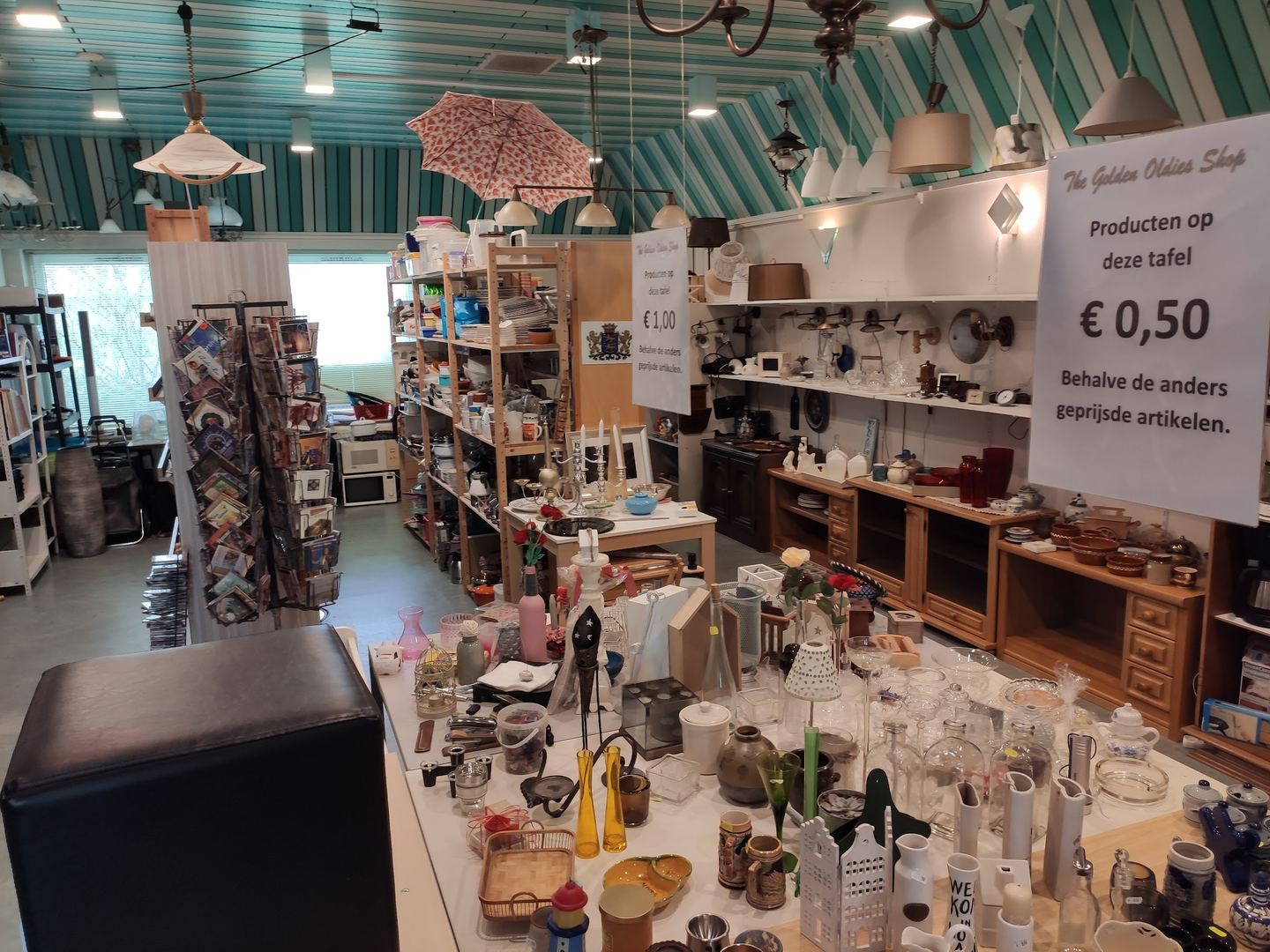 Interieur van The Golden Oldies Shop met schappen vol servies, glaswerk, lampen en kleingoed