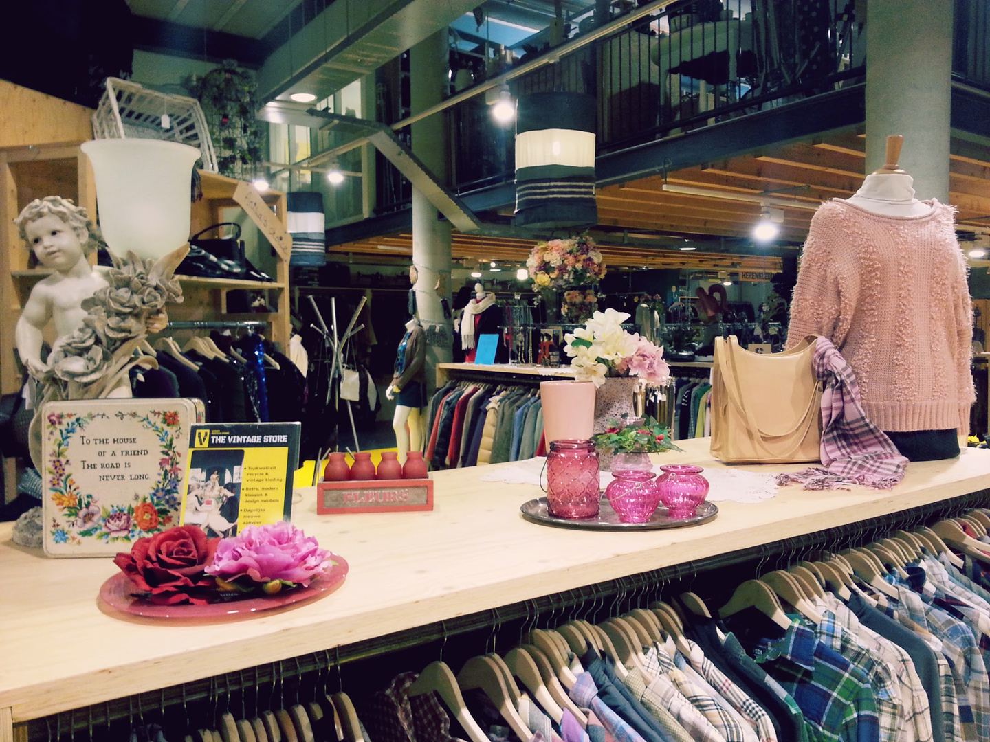 Rekken met vintage kleding en een toonbank met decoratie in The Vintage Store