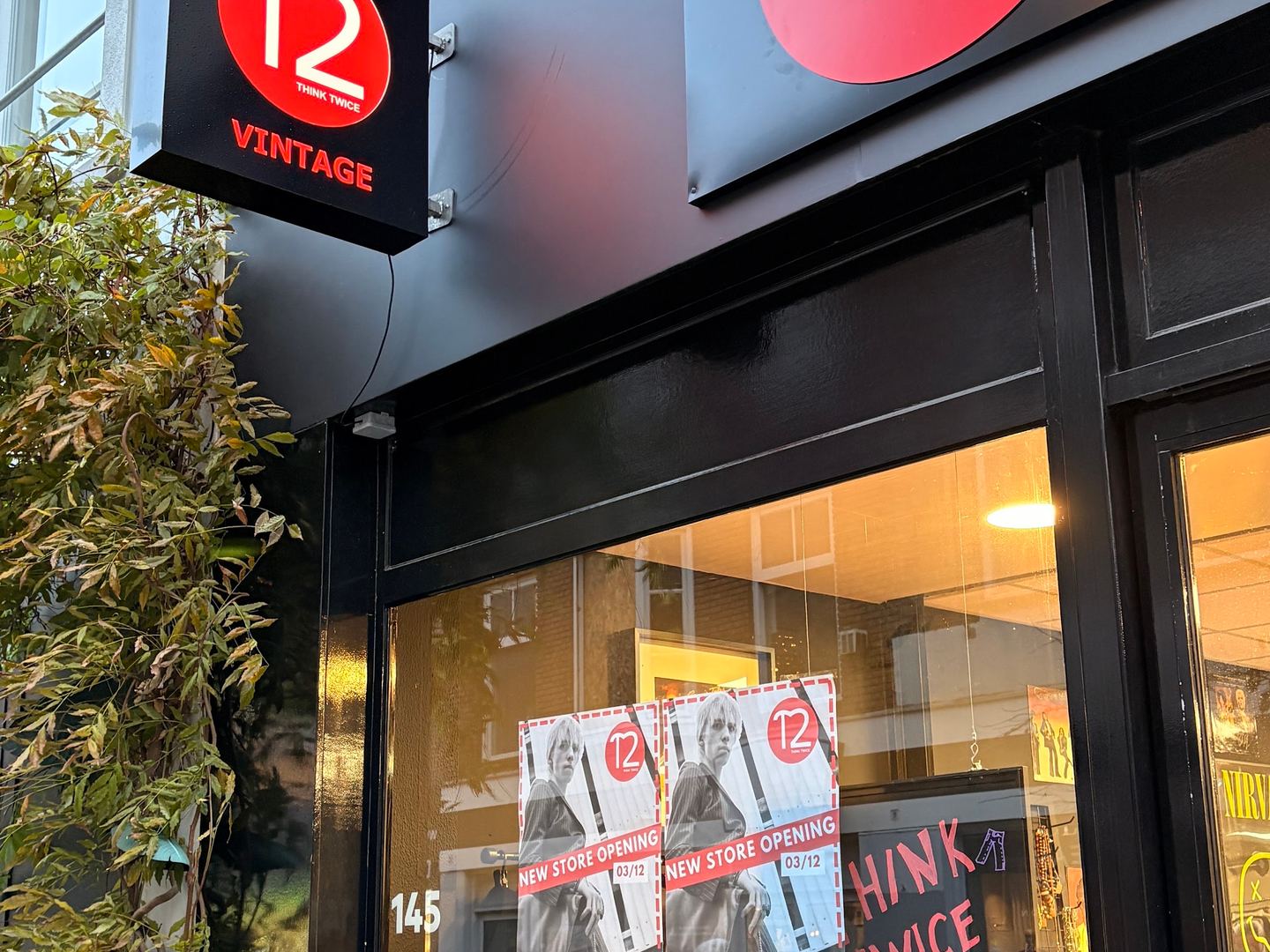 Gevel van Think Twice met rood T2-logo, uithangbord en etalage met kleding