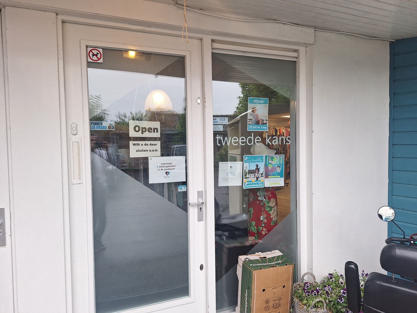 Ingang van Tweede Kans met open-bordje en de naam op het glas van de deur
