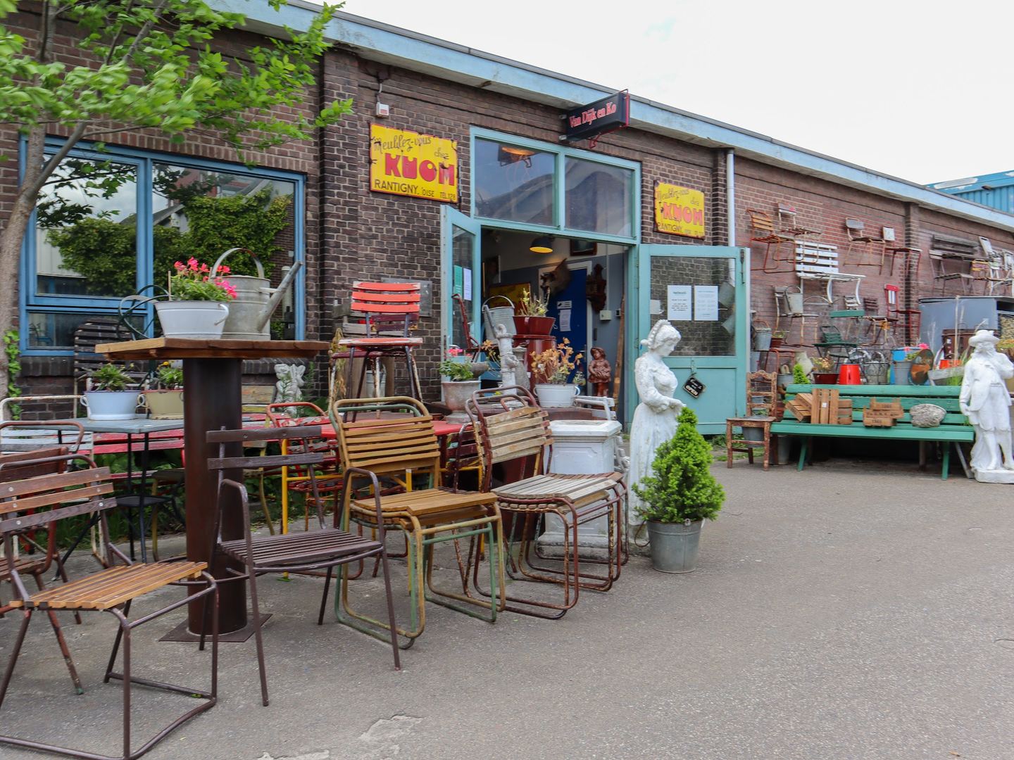Winkelpui van Van Dijk & Ko met stoelen, tafels en beelden buiten voor de ingang