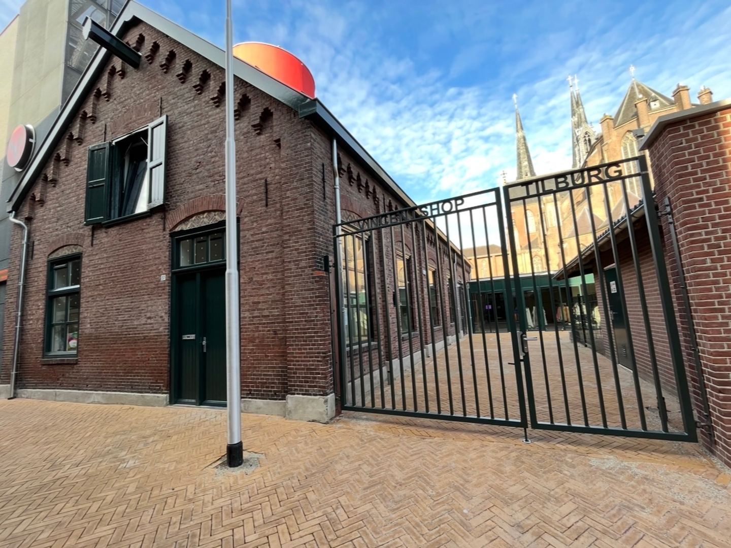 Gevel van de Vincentshop met een smeedijzeren poort en bord in een bakstenen pand