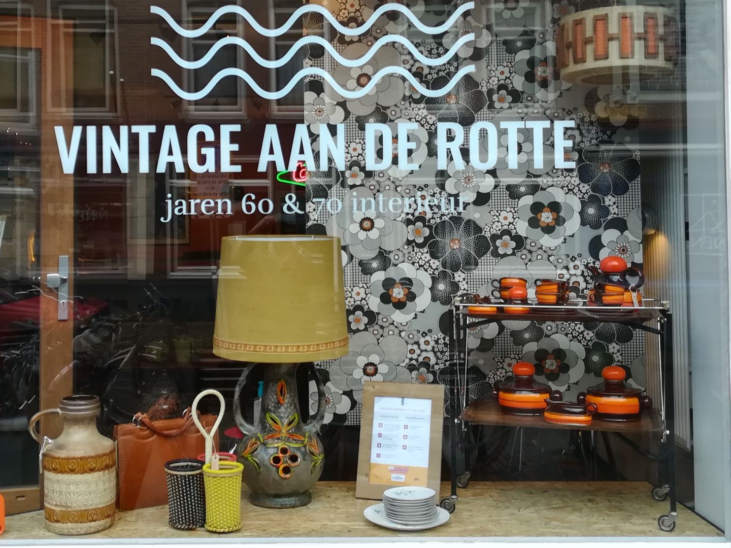 Etalage van Vintage aan de Rotte met de winkelnaam op het raam en jaren-60-servies, lampen en vazen