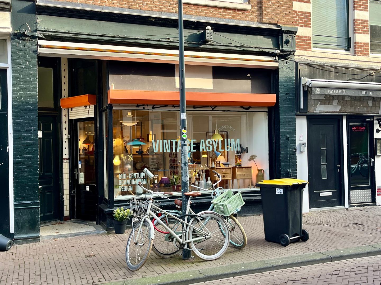 Gevel van Vintage Asylum met belettering op de etalageruit en vintage lampen achter het glas