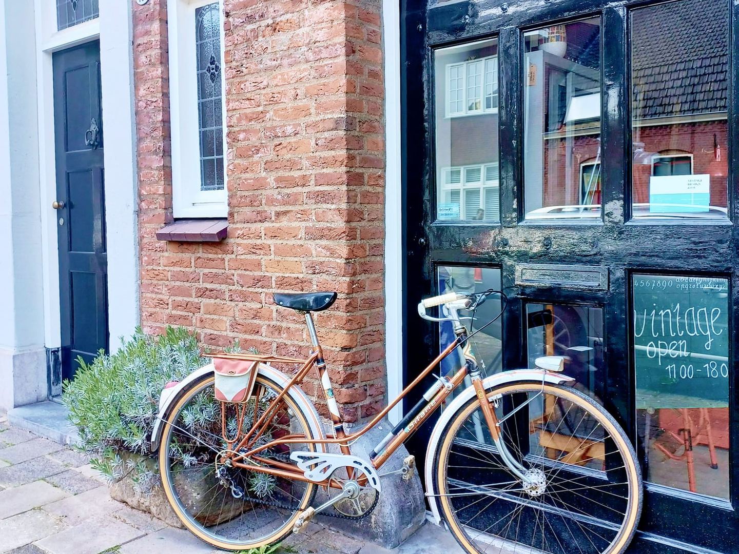 Gevel van Vintage Design & Co. met uithangbord, fiets en etalage met vintage-bord