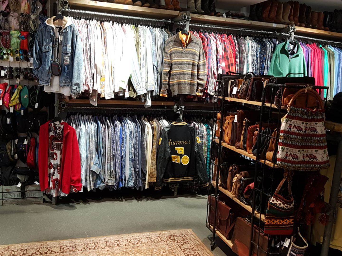Interieur van Vintage Island Utrecht met rekken vol vintage jacks, overhemden en truien en een kast met leren tassen