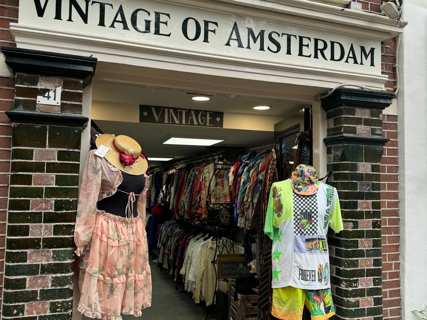 Gevel van Vintage of Amsterdam met kleding op rekken bij de ingang