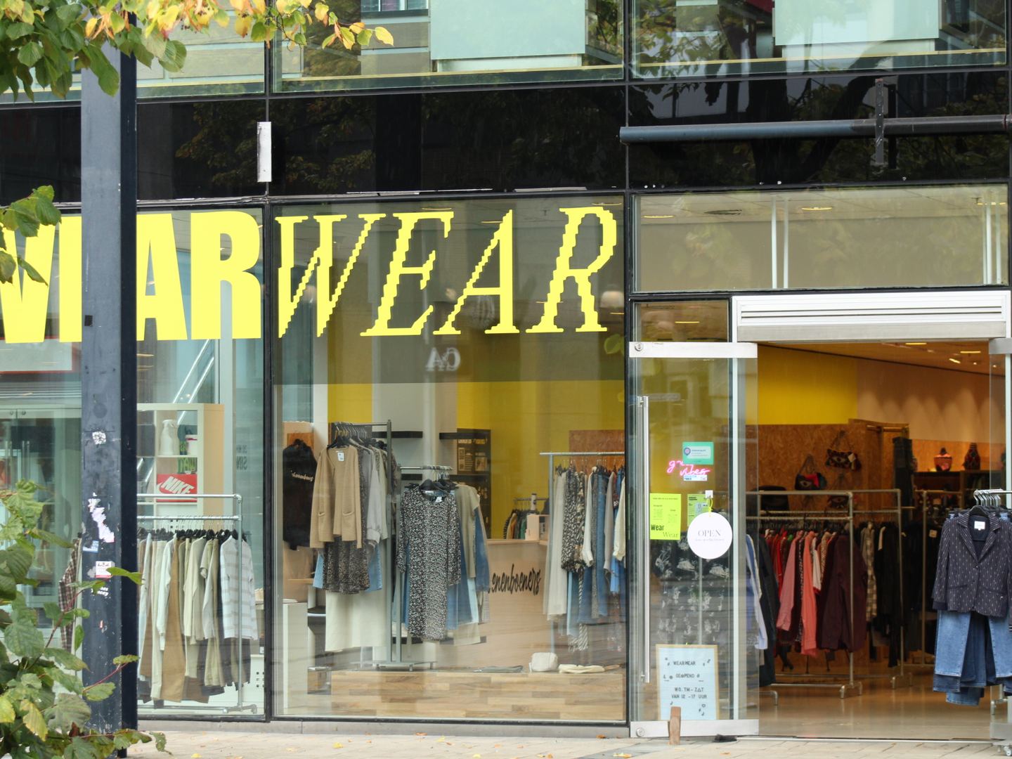 Winkelpui van WearWear met gele letters en rekken met tweedehands kleding achter het glas