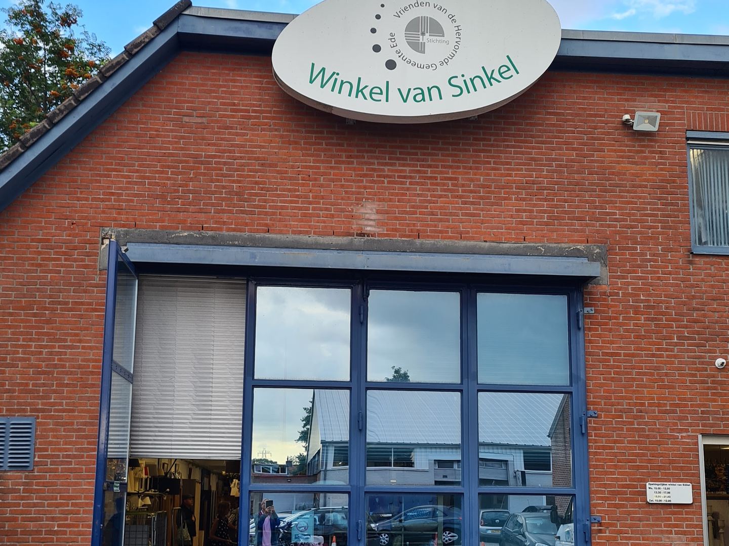 Gevel van Winkel van Sinkel met naambord boven de glazen deuren