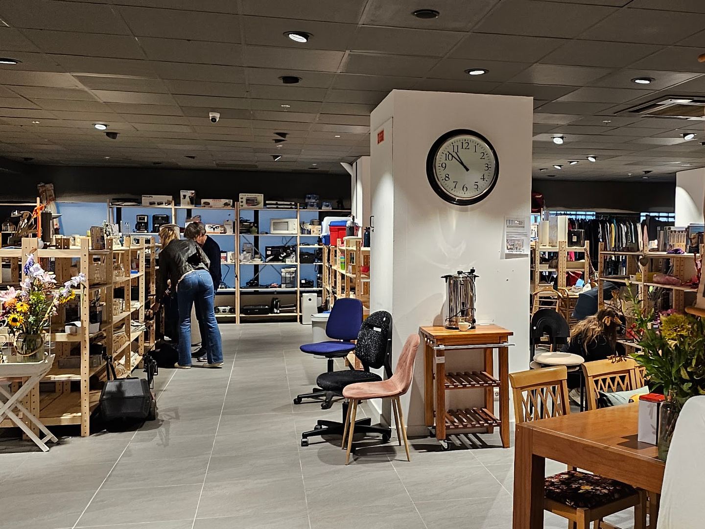 Interieur van Woord en Daad Winkel Houten met houten schappen vol huisraad, stoelen en tafels