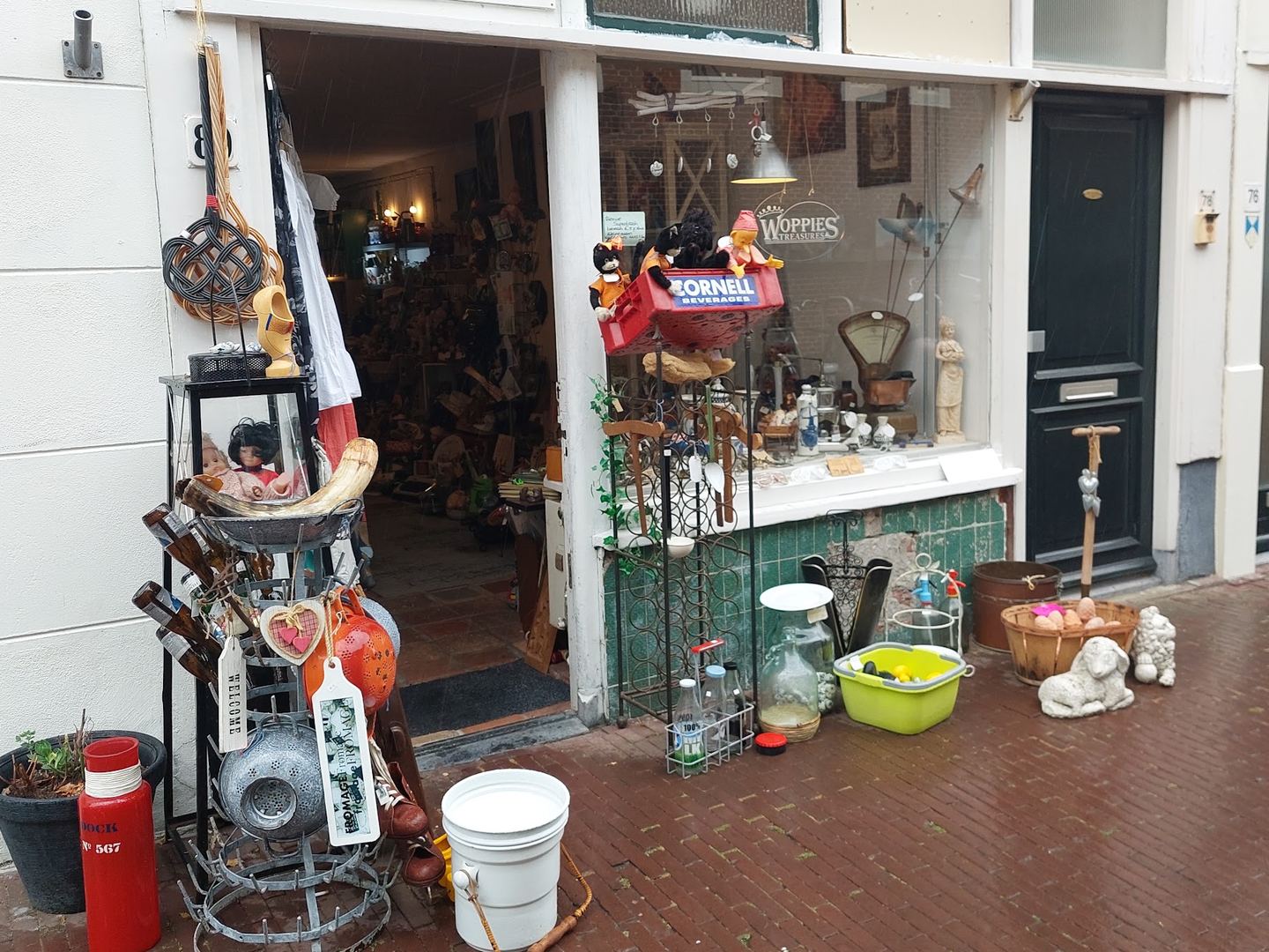 Winkelpui van Woppies Treasures met naam op de etalage en curiosa en brocante uitgestald op de stoep